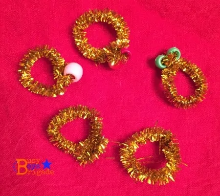5 rings made out of gold pipe cleaners and craft beads