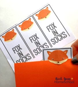 fox in socks bookmark on an orange piece of paper to demonstrate how the assembled bookmark looks