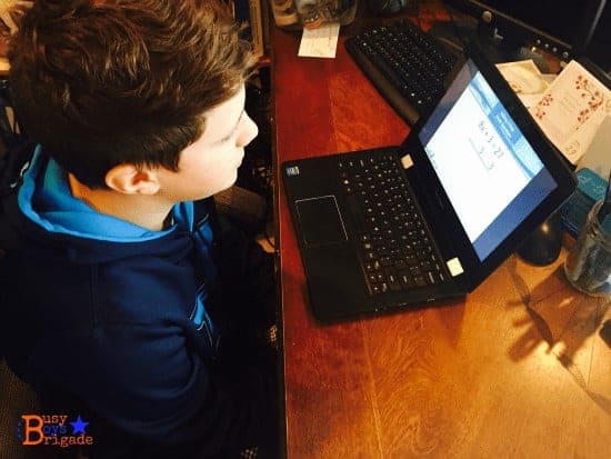 A young boy using a laptop computer sitting on top of a table for Homeschool Pre-Algebra Mr. D Math