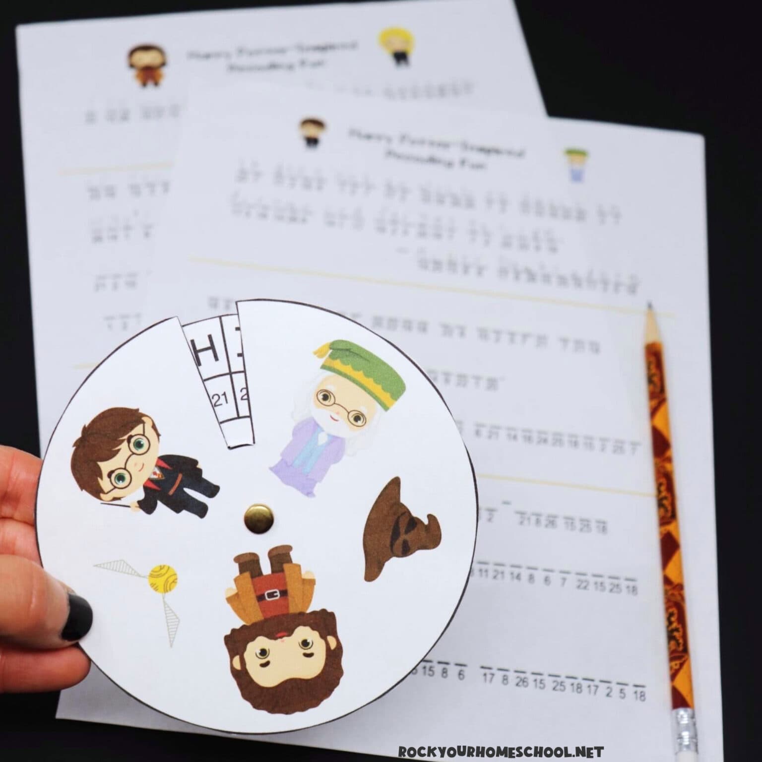 Woman holding Harry Potter decoder ring with free printable decoding activities in background.