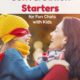 Mom wearing maroon sweater holding daughter wearing gold knit cap, red eye mask, & blue sweater