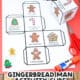 Gingerbread man activity cube printable page and cube with scissors and glue stick on red paper with wood background.