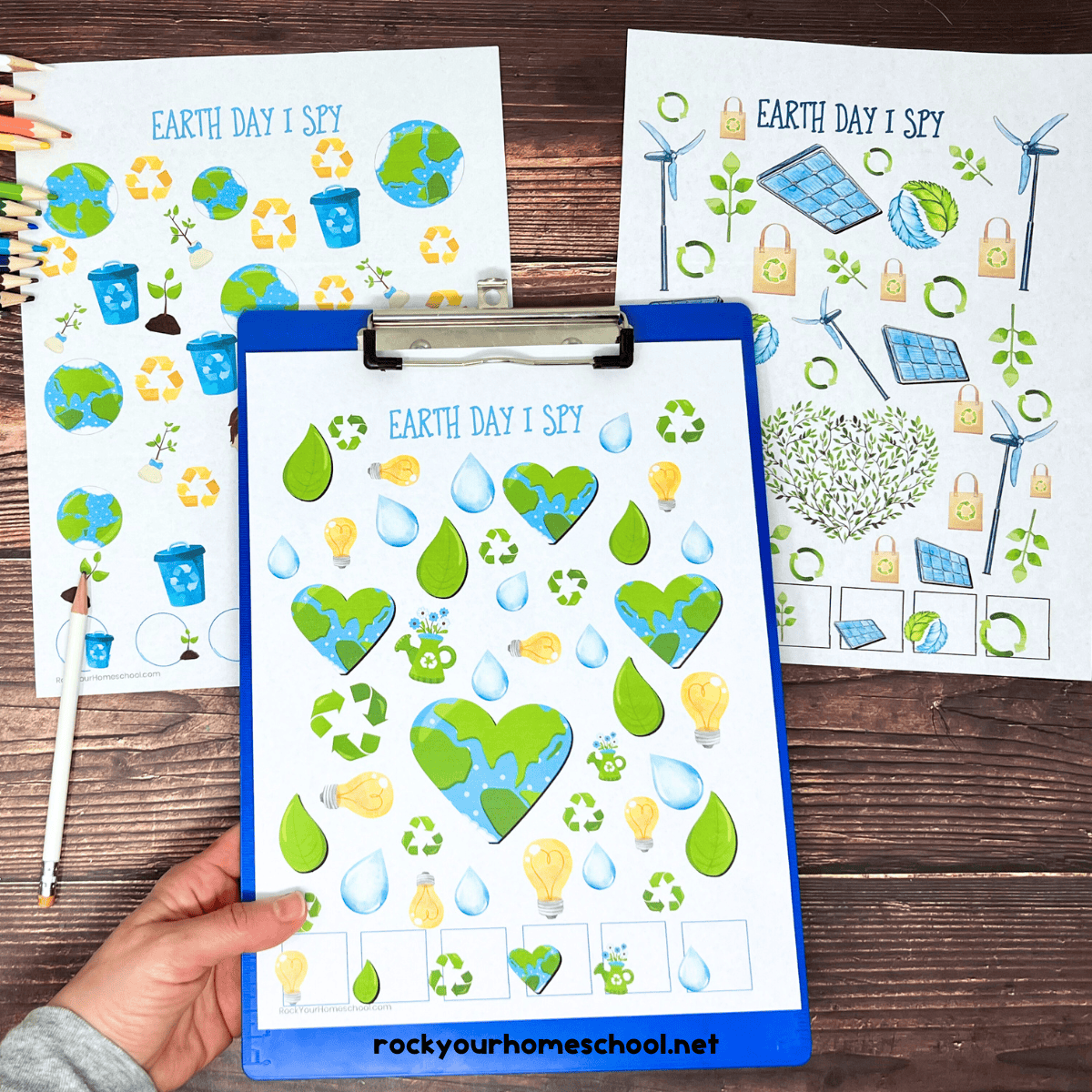 Woman holding blue clipboard with free printable Earth Day activities for kids for I Spy fun.