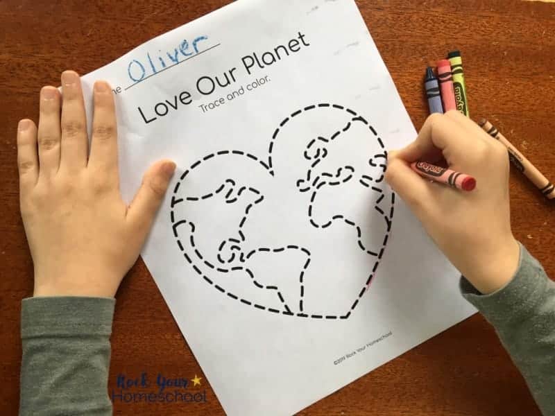 Boy using crayon on Earth Day tracing page.