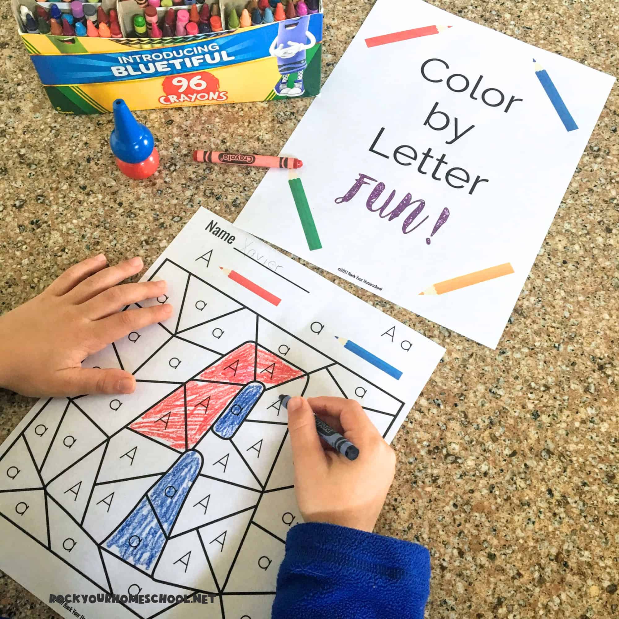 Boy using blue crayon to work on free printable color by letter fun page featuring the letter Aa.