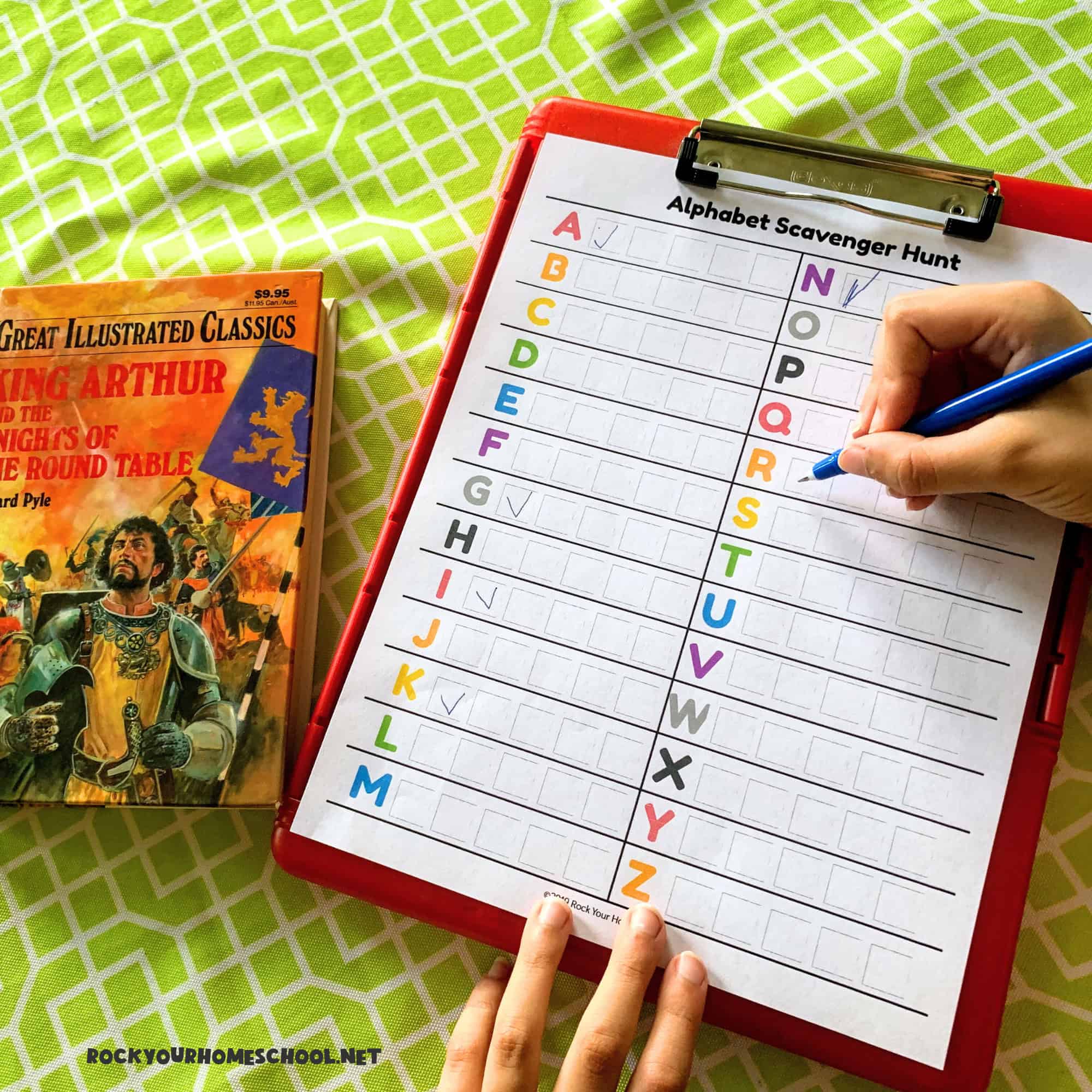 Boy working on free printable alphabet scavenger hunt activity with book.