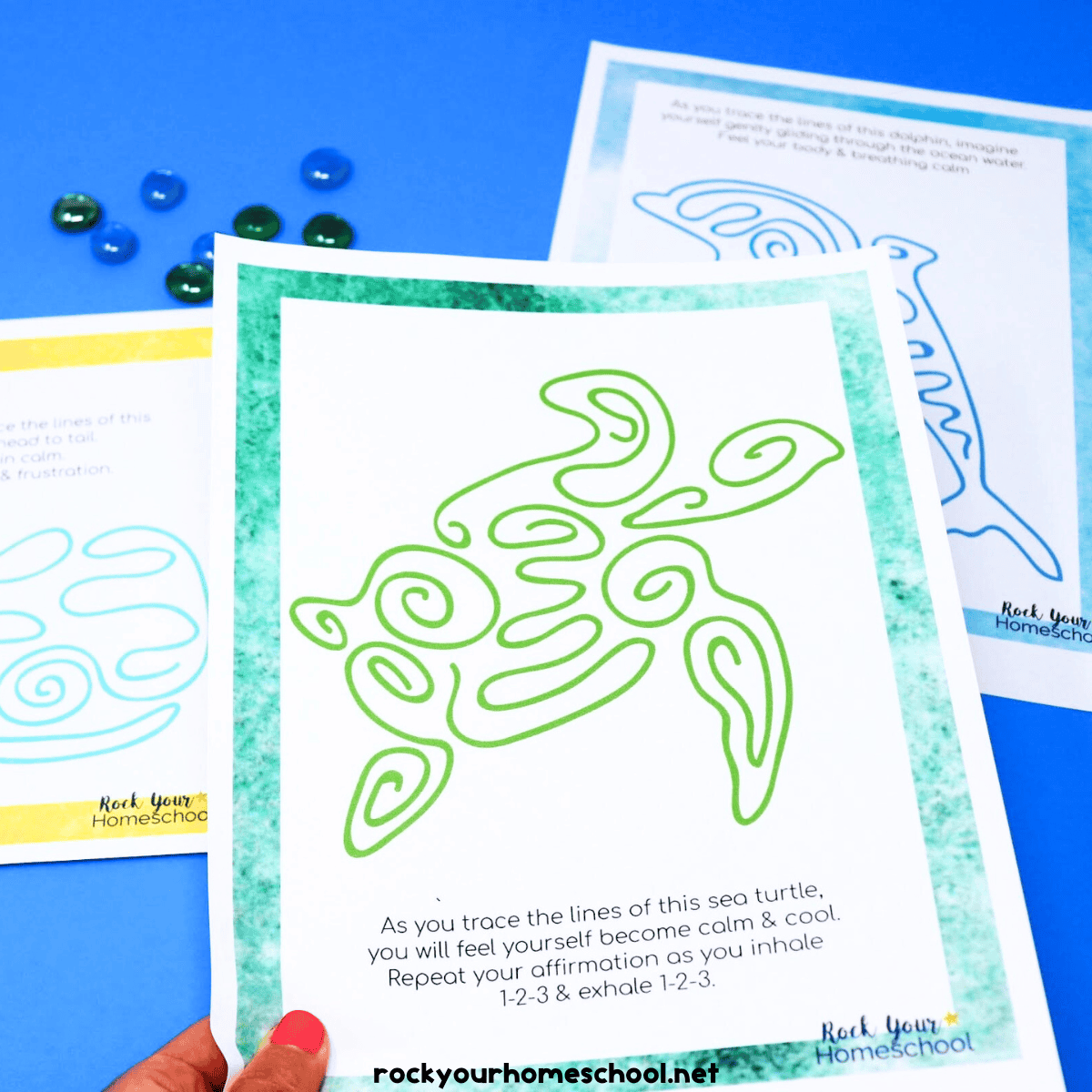 Woman holding example of free printable mindfulness activities for kids featuring a sea turtle, dolphin, and whale.