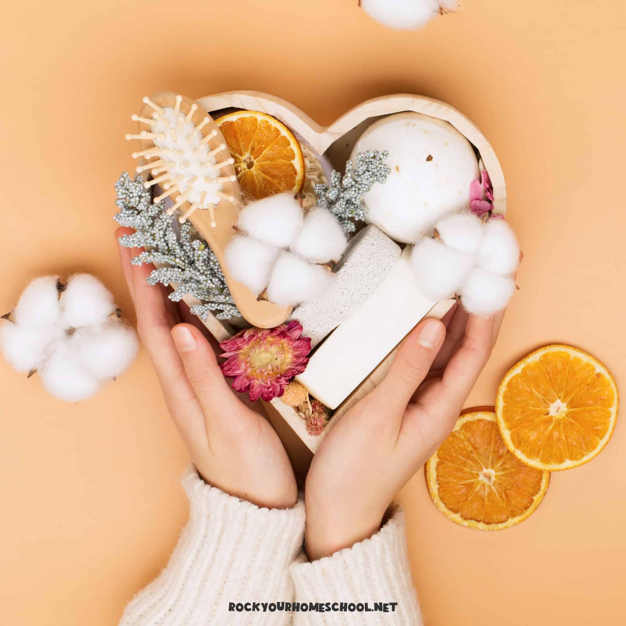 Woman holding-heart-shaped basket with dried orange slices, cotton balls, soap, and more for the best self-care gift ideas.