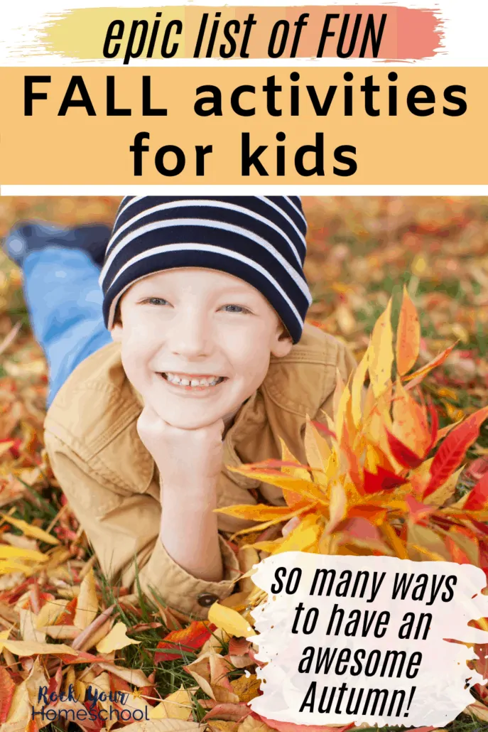 Boy smiling with a navy striped hat on & laying in leaves to feature this epic list of fun Fall activities for kids and families