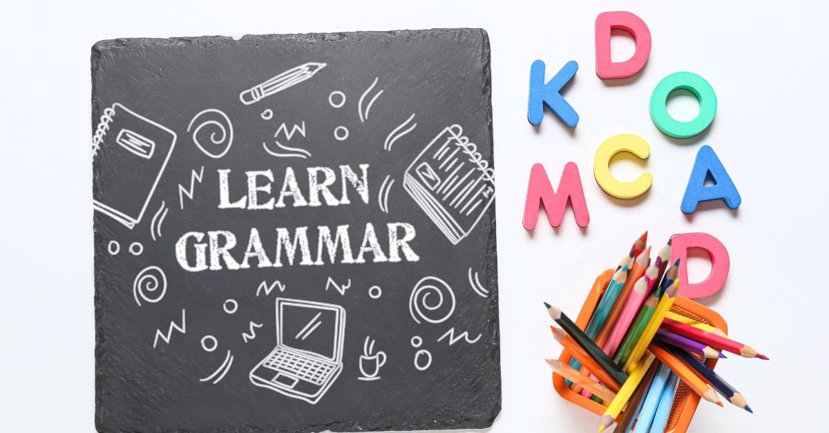 Learn Grammar written with white chalk on blackboard with foam letters and pencils.