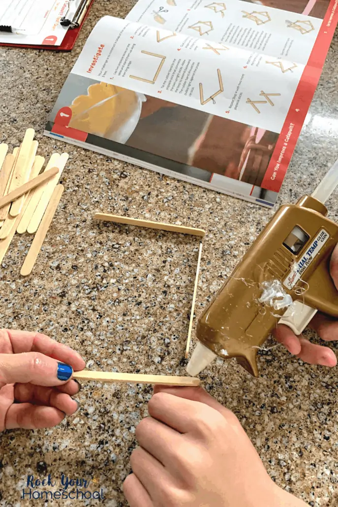 Tween boy using hot glue gun to build a catapult out of popsicle sticks and rubber bands to show the awesome science activities found in BookShark Science packages
