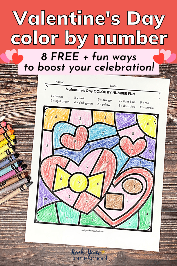 Valentine's Day color by number page featuring heart-shaped box of chocolates with crayons on wood background
