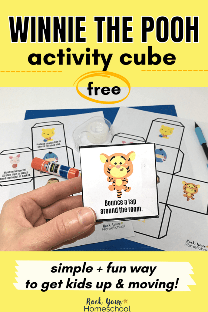 Boy holding free Winnie the Pooh activity cube with cute Tigger on front with printable page, glue sticks, and scissors in background