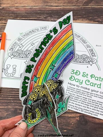 Woman holding free printable St. Patrick's Day 3D card for coloring fun.