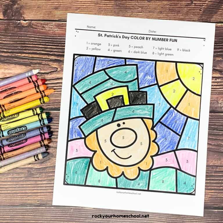 St. Patrick's Day color by number pages with a leprechaun and horseshoe and three-leaf clover with crayons on wood surface.