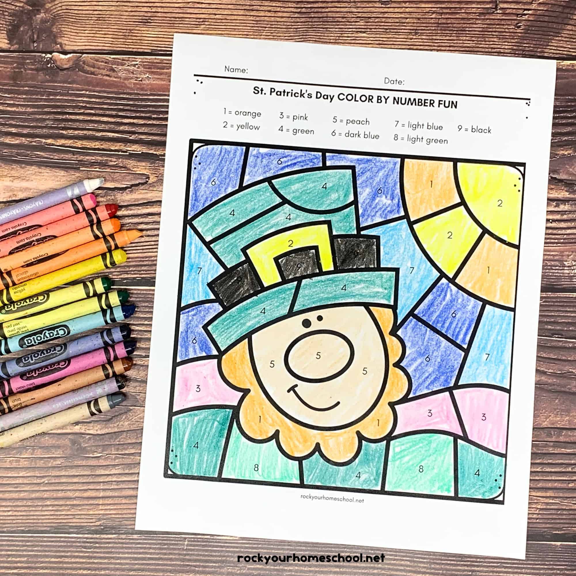 St. Patrick's Day color by number pages with a leprechaun and horseshoe and three-leaf clover with crayons on wood surface.