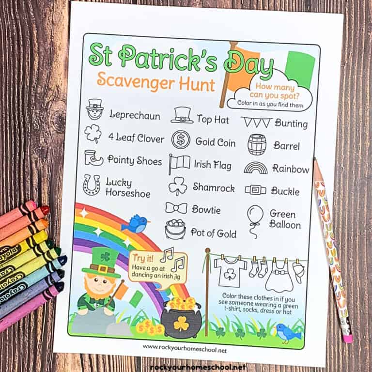 free printable St. Patrick's Day scavenger hunt with crayons and pencils with rainbows on wood surface.