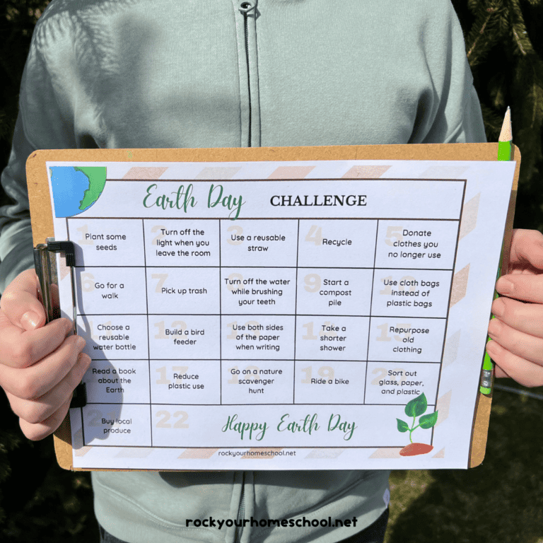 Boy holding clipboard and green pencil with free printable Earth Day challenge.