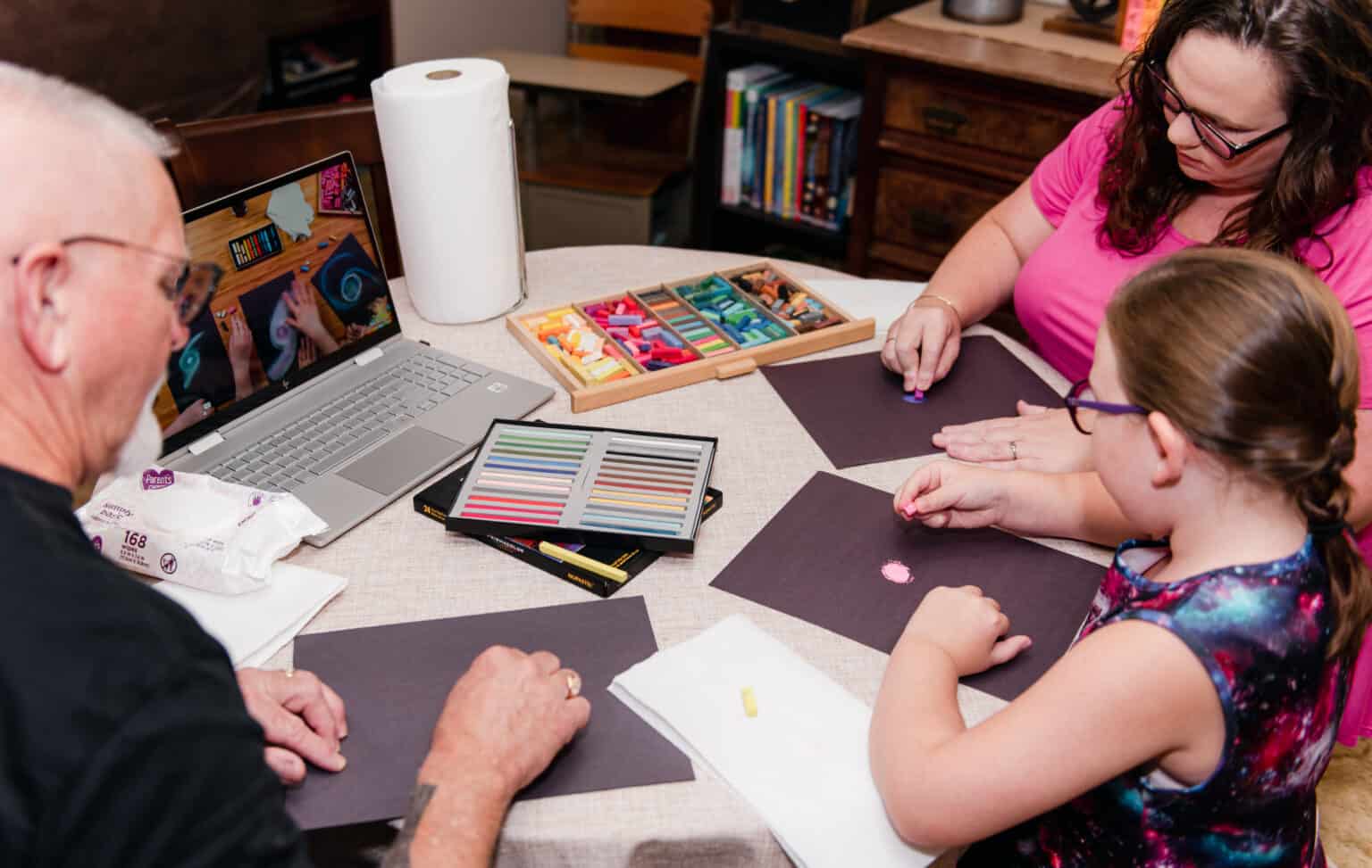 Jessica of The Waldock Way with her husband and daughter enjoying a chalk pastel lesson to feature how to make homeschooling an only child fun