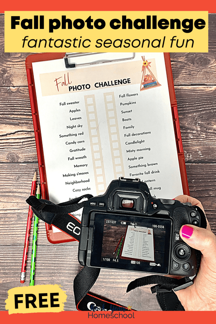 woman holding camera with free printable Fall photo challenge on red clipboard and pencils on wood background