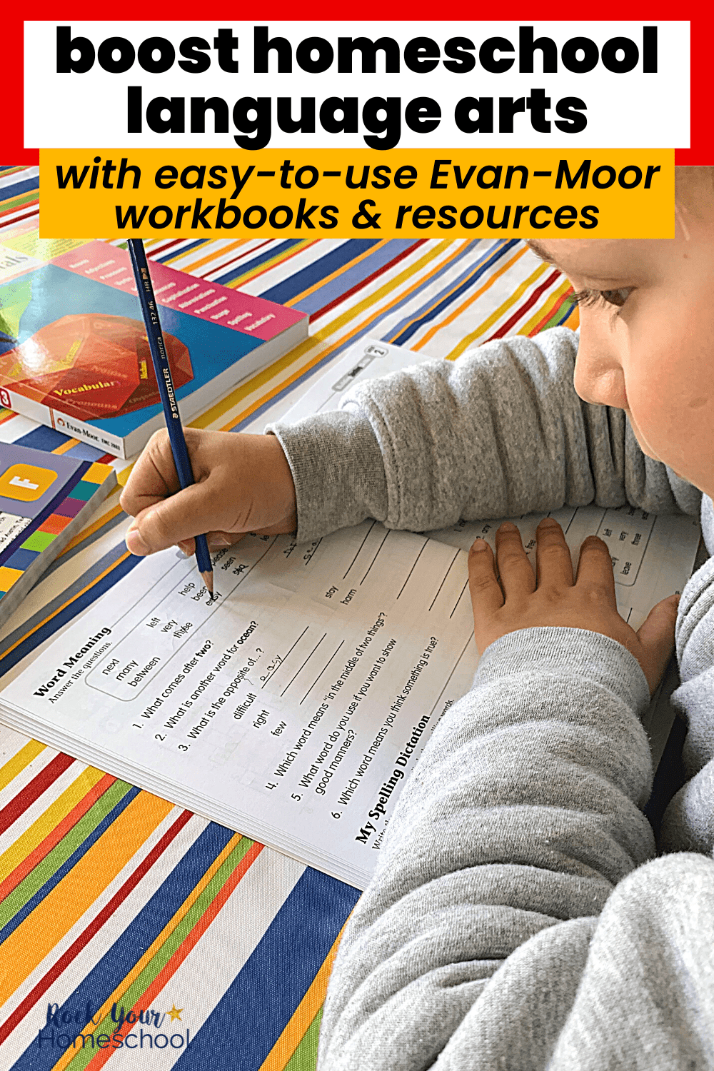 Young boy using blue pencil in spelling workbook with other Evan-Moor workbooks in background