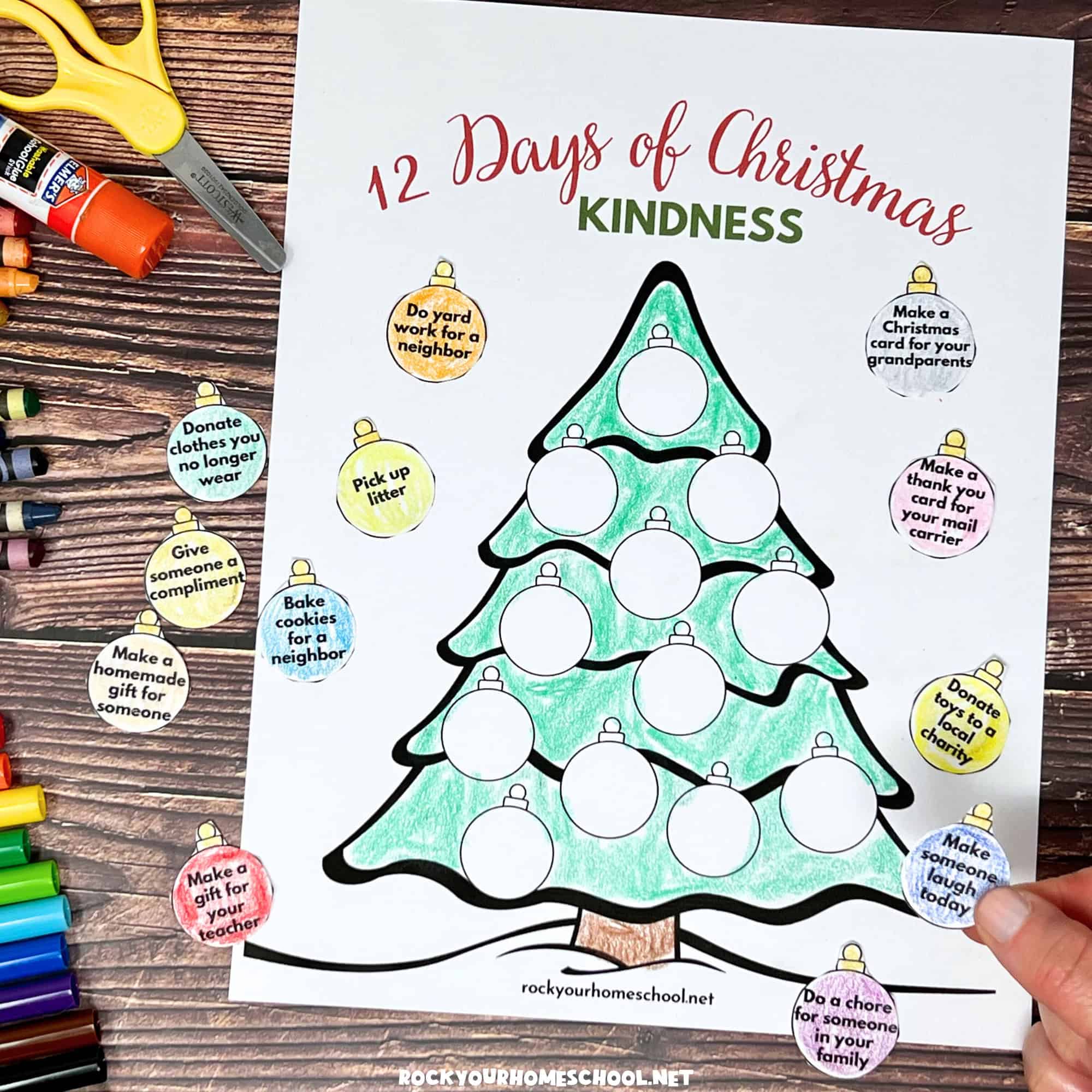 Woman holding example of free printable Christmas random acts of kindness activity with tree and ornaments.
