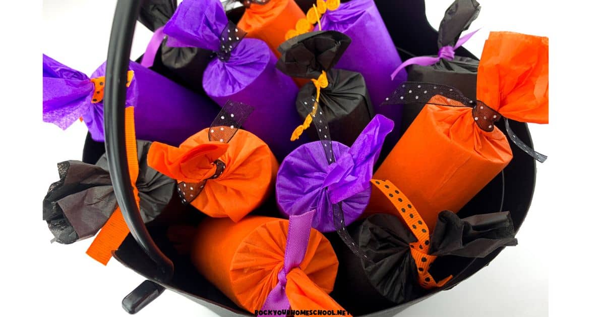 Black plastic basket full of DIY Halloween party poppers in purple, orange, and black.