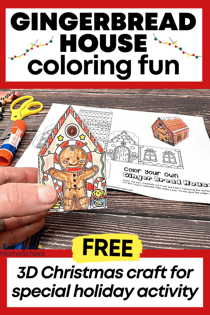 woman holding example of 3D Christmas craft of printable gingerbread house coloring page with crayons, yellow scissors, and glue stick on wood background