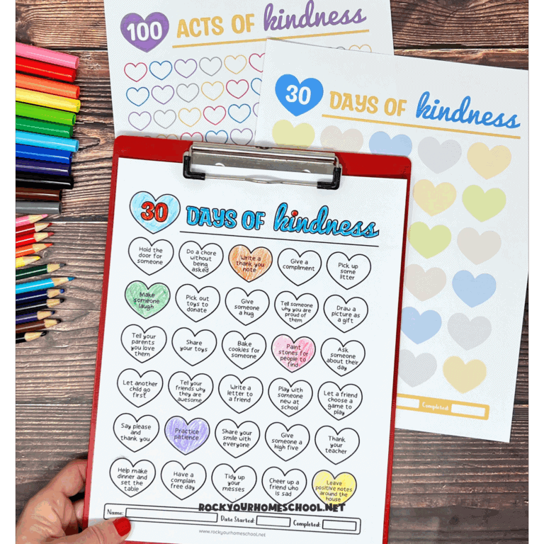Examples of free printable kindness activities for kids on red clipboard and wood background with rainbow of markers and color pencils.