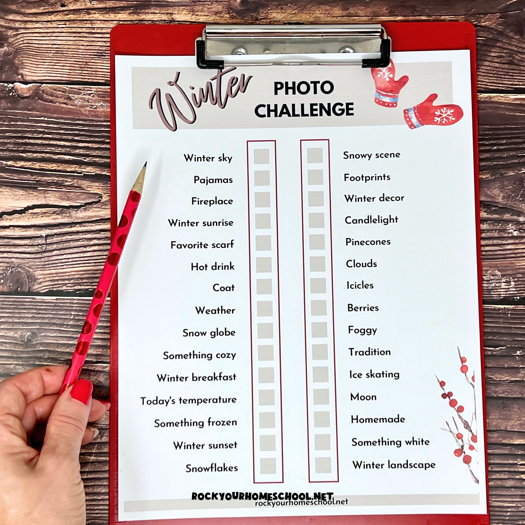 Woman holding free printable winter photo challenge on red clipboard with red pencil on wood background.