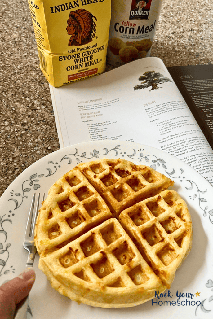 Cheddar and cornbread waffle on plate with corn meal and recipe in background.