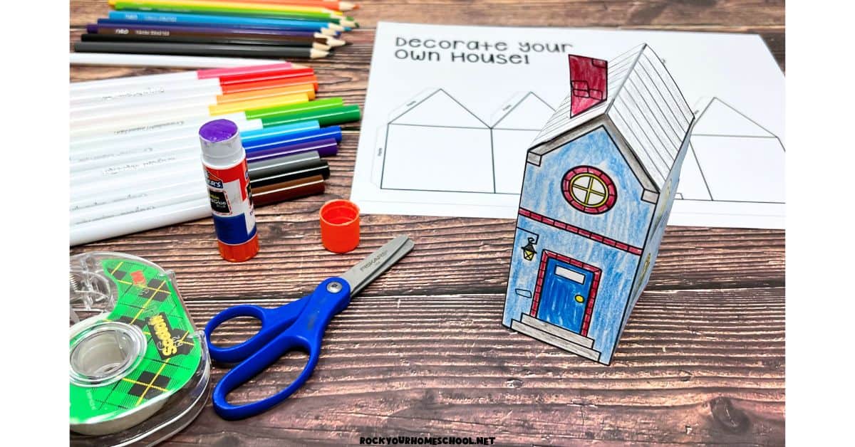 Example of 3D paper house template and craft with color pencils, markers, glue stick, scissors, and tape.