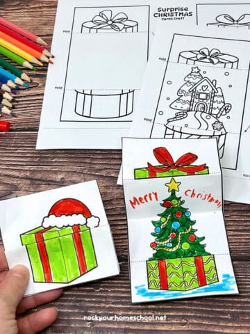 Woman holding DIY coloring card with other templates and examples of free Christmas cards for kids.