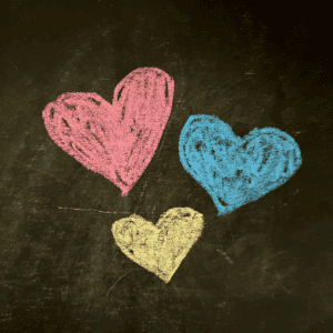 Black chalkboard with chalk hearts in pink, blue, and yellow.