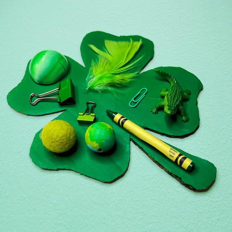 Example of a monochromatic shamrock collage with green crayon, ball, small toy, paper clip, and more.