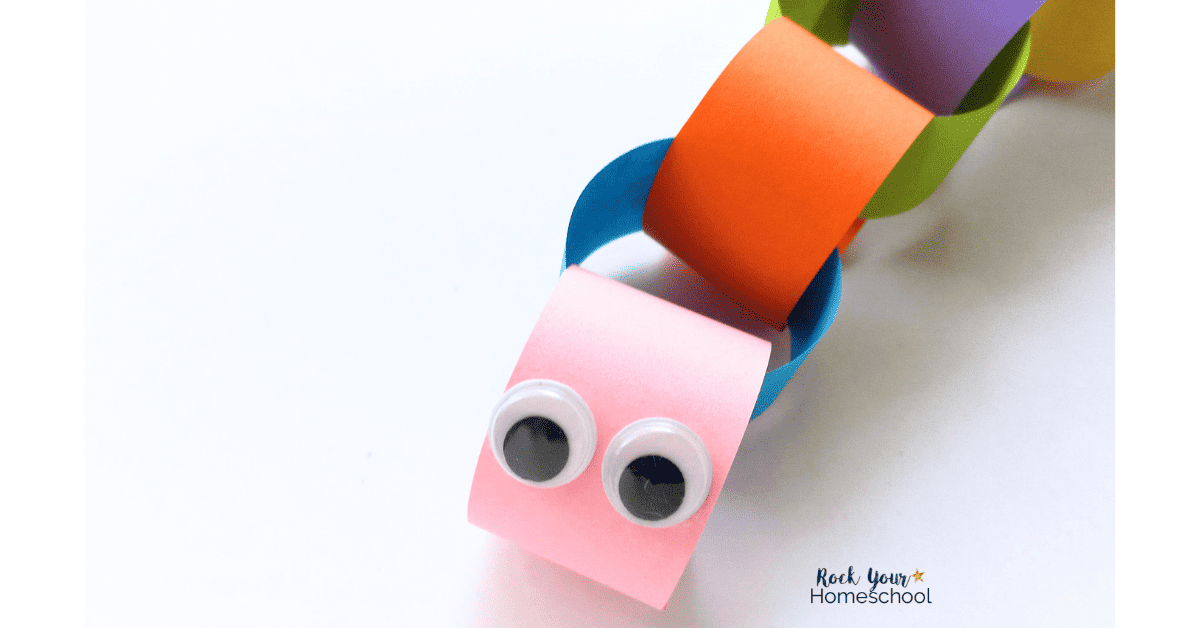 Pair of googly eyes on pink paper link chain for caterpillar craft.