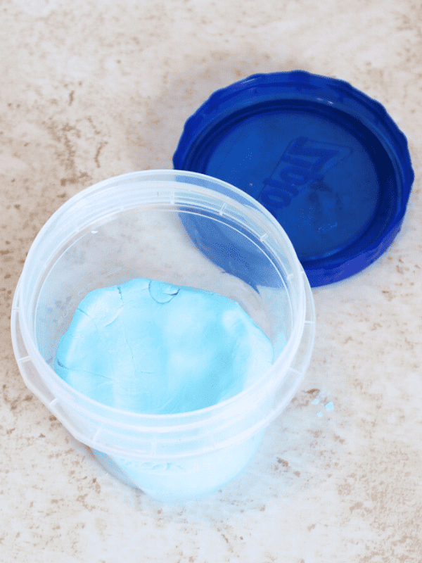 Cloud dough in plastic container with blue lid.