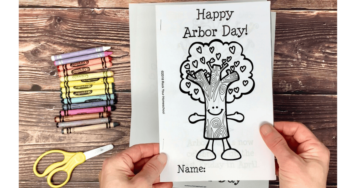Woman holding example of free printable Arbor Day mini-book with crayons and scissors.