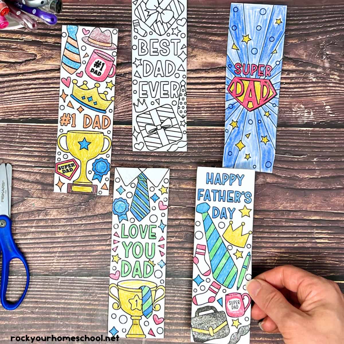 Woman holding Father's Day bookmarks to color with gel pens and scissors.