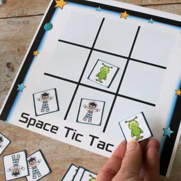 Woman holding alien card for printable Alien vs. Astronaut tic tac toe game.
