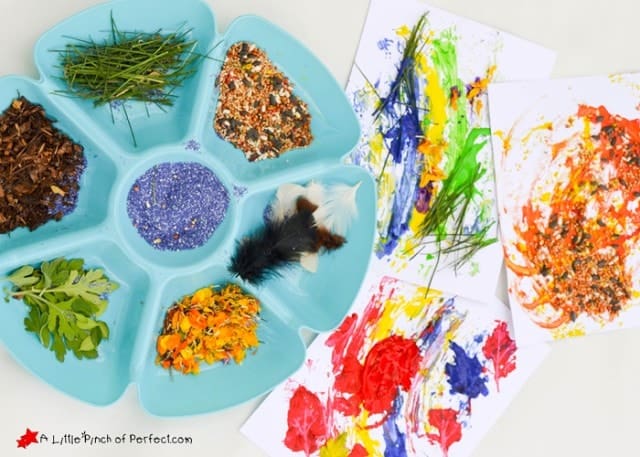 Nature painting kids activity with seeds, bird feathers, grass, and paint.