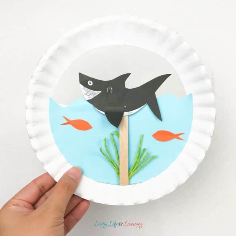 Person holding example of shark paper plate craft.