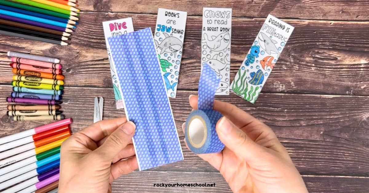 Woman holding blue washi tape with shark coloring bookmark.
