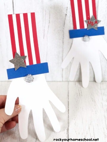 Woman holding example of Uncle Sam handprint craft with another example in background.