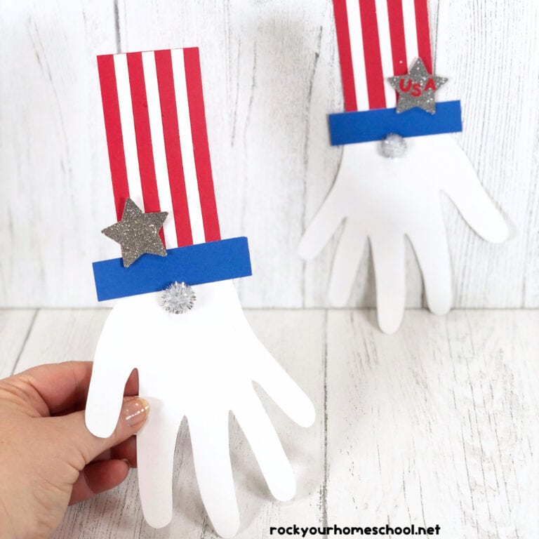 Woman holding example of Uncle Sam handprint craft with another example in background.