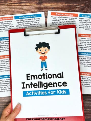 Woman holding clipboard with cover of emotional intelligence activities for kids pack with lists in background.
