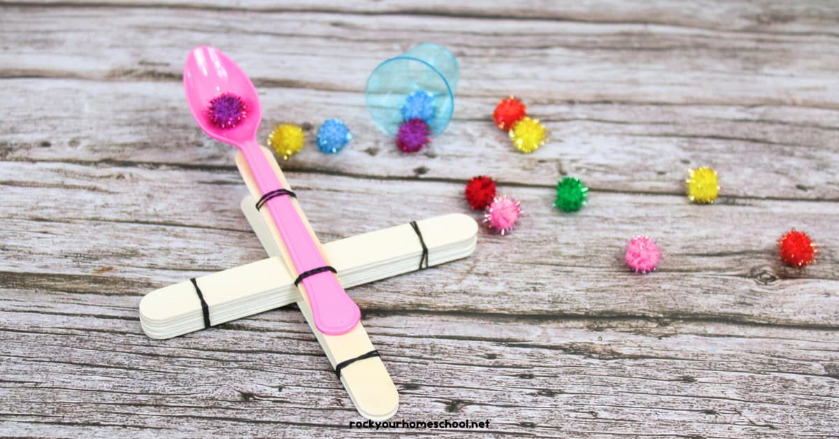 Example of DIY catapult made with wood craft sticks, rubber bands, and pom poms.