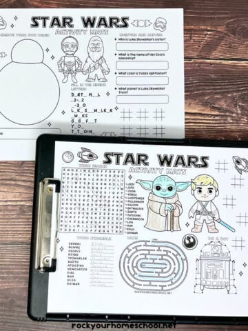 Woman holding black clipboard with examples of Star Wars activity sheets.