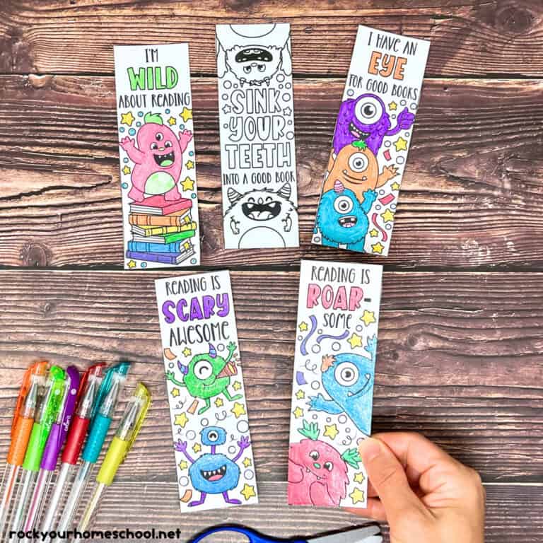 Woman holding examples of free printable monster bookmarks to color with gel pens.