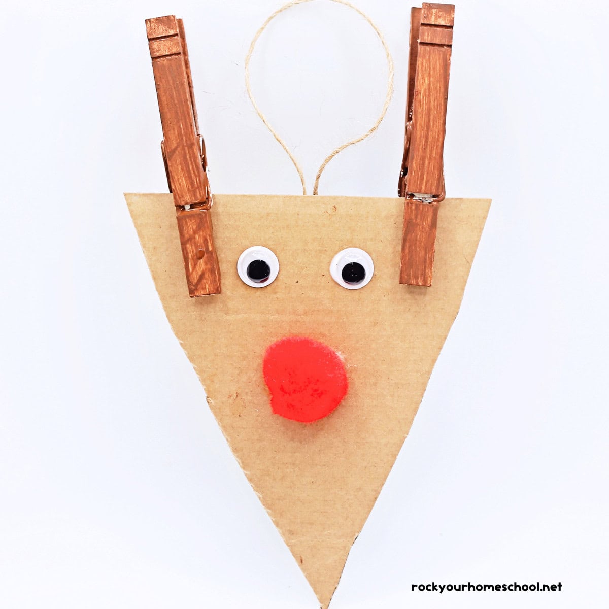 Cardboard triangle with googly eyes, red pom pom, and two brown clothespins.